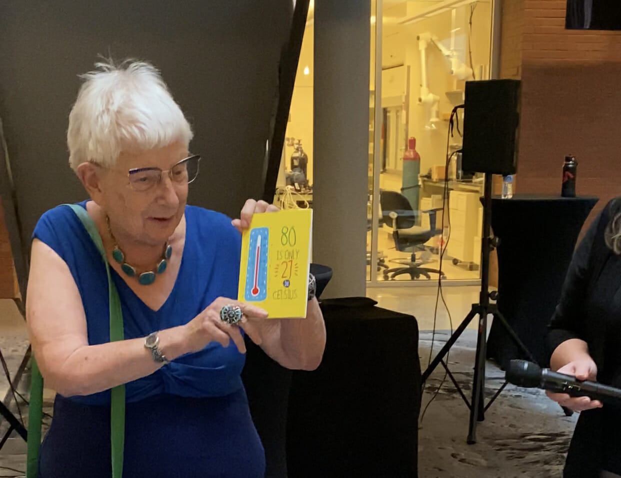 A photograph of Alex Navrotsky holding up a birthday card that reads: 