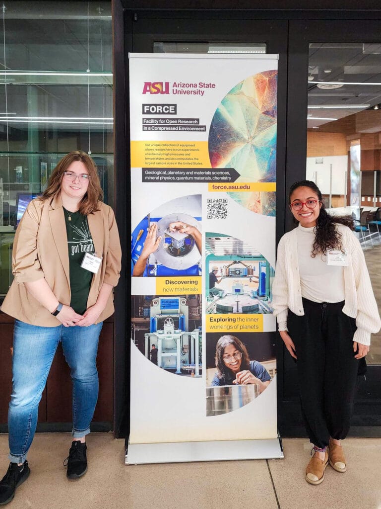 A photo of two women standing next to a tall pop-up banner